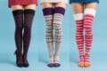Three women display their colorful knitted socks, each pair featuring different designs and bright colors for a cozy look.