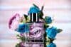 A niche fragrance perfume bottle adorned with blue and pink roses, elegantly placed on a table.