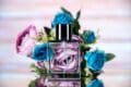 A niche fragrance perfume bottle adorned with blue and pink roses, elegantly placed on a table.