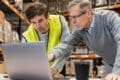 Two men in a warehouse working together on a laptop related to customs clearance