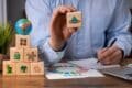 Man holding wooden blocks featuring eco-friendly symbols representing key aspects of sustainability.