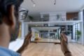 A man holds a tablet displaying a virtual home, showcasing modern design and interactive features.