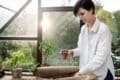 A woman holds a plant pot inside a paper bag, showcasing her love for plants and nature.