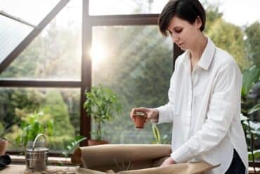 A woman holds a plant pot inside a paper bag, showcasing her love for plants and nature.