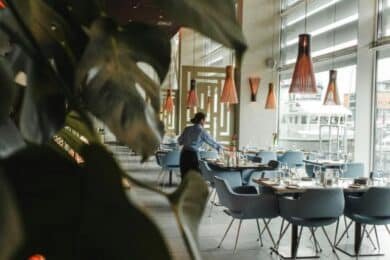 A cozy American restaurant featuring blue chairs and a large window, inviting natural light inside.