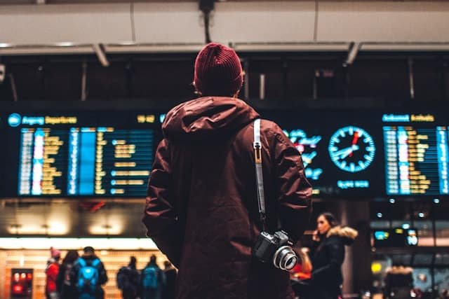 A man in a red coat stands at an airport, symbolizing the surge in American travel post-pandemic.