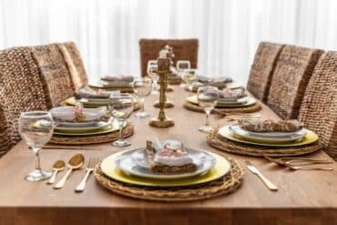 A beautifully set dinner table with elegant dishes and a wicker chair, showcasing Ashley Furniture dining sets.
