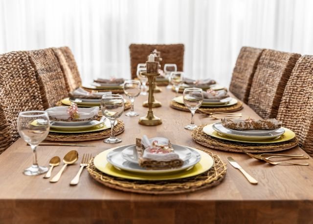 A beautifully set dinner table with elegant dishes and a wicker chair, showcasing Ashley Furniture dining sets.