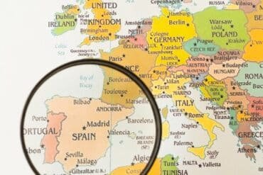 Magnifying glass focused on a map of Europe, highlighting the city of Bess in Spain.