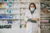 A female pharmacist assisting customers in the Centerwell Pharmacy, surrounded by shelves of medication and health products.