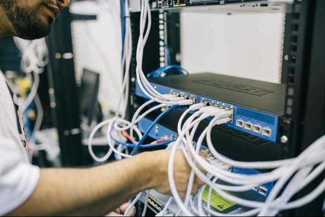 A man works on a server in a data center for Diamond Communications, focused on maintaining the equipment.