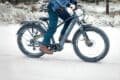 A man rides a bike through a snowy landscape, showcasing winter cycling in action.
