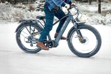 A man rides a bike through a snowy landscape, showcasing winter cycling in action.