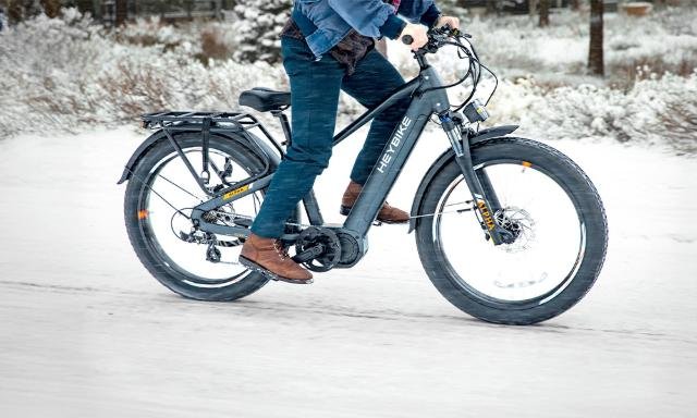 A man rides a bike through a snowy landscape, showcasing winter cycling in action.