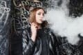 A woman in a leather jacket exhales vapor from an MR FOG.