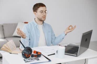 A man with headphones is seated at a desk, engaged with his laptop, creating a productive workspace.