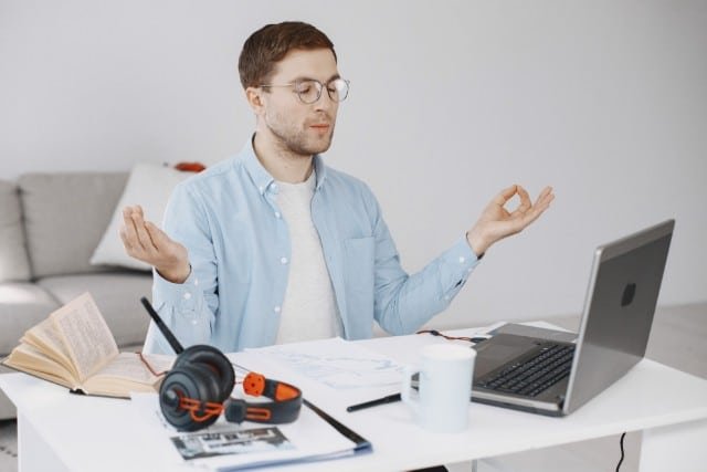 A man with headphones is seated at a desk, engaged with his laptop, creating a productive workspace.
