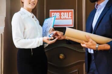 A man and woman display a "For Sale" sign, highlighting upcoming property auctions nearby.