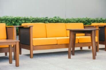Cozy courtyard featuring a collection of orange and brown teak wood furniture.
