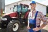 Smiling man in front of a tractor, representing a Tractor Supply Sales Associate role.