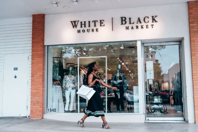 A woman walks by a white building marked as a black market store, with a curious expression on her face.