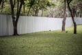 A metal privacy fence stands in the center of a lush grassy area, providing a boundary in the open space.