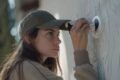 A woman wearing a cap looks directly at the camera, highlighting her involvement in security camera installation.