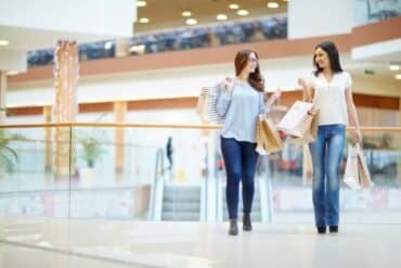 Two friends enjoy a day at Burlington Mall, walking with shopping bags in hand.