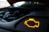 Car engine with illuminated battery and a flashing check engine light, indicating a potential issue needing attention.