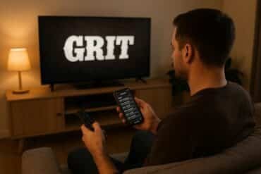 Man watching TV with remote, focused on the Grit TV schedule displayed on the screen.