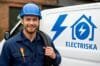 Electrician standing in front of a van with "Närkes Elektriska" sign, ready to assist with electrical services.