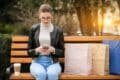 A woman sits on a bench with shopping bags, reflecting how online shopping has transformed daily habits.