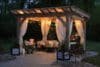 A beautifully lit gazebo adorned with flowing curtains, creating a cozy and inviting atmosphere.