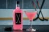A pink drink labeled Pink Whitney with a hockey stick blurred in the background.