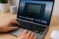 A person typing on a Mac laptop, focused on their work with a clear screen in front of them.