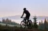 A man rides a mountain bike on a rugged trail surrounded by majestic mountains.