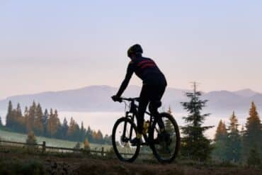 A man rides a mountain bike on a rugged trail surrounded by majestic mountains.