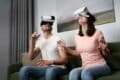 A man and woman enjoy virtual reality experiences together on a couch, wearing VR glasses at ANVIO.