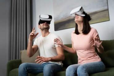 A man and woman enjoy virtual reality experiences together on a couch, wearing VR glasses at ANVIO.