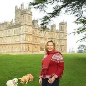 A woman in a red sweater and jeans stands with two dogs in front of Abbey Castle in London.