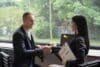 A man and woman shaking hands in a modern office setting, symbolizing a successful business agreement.