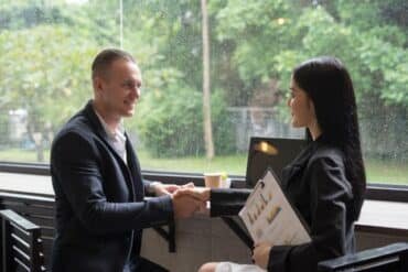 A man and woman shaking hands in a modern office setting, symbolizing a successful business agreement.