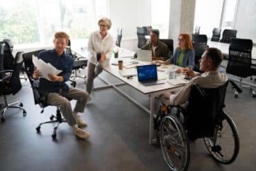 People in wheelchairs collaborating in a bright office space, showcasing an inclusive work environment.