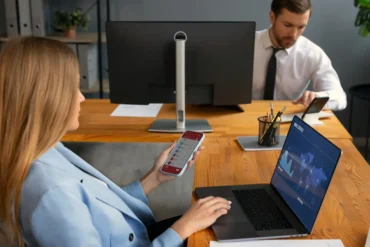 A woman uses a remote control to operate a laptop, illustrating technology in healthcare property loan management.