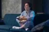 A woman seated on a couch holds a bowl of popcorn, engaged with HD Hub 4 U Streaming.