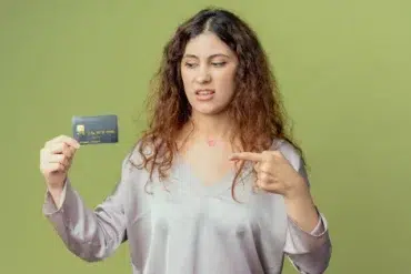 A woman holds a credit card and points at it, suggesting a discussion about the Milestone Credit Card's benefits.