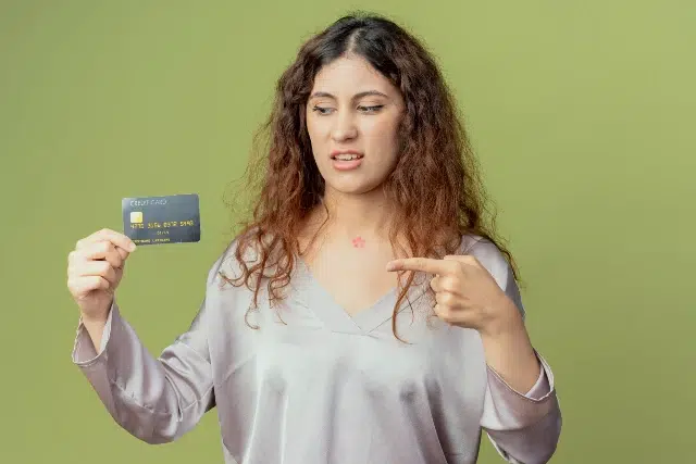 A woman holds a credit card and points at it, suggesting a discussion about the Milestone Credit Card's benefits.