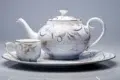 A white and gold teapot and cup elegantly placed on a plate, showcasing the design from Machine a The Choisir.Guide.