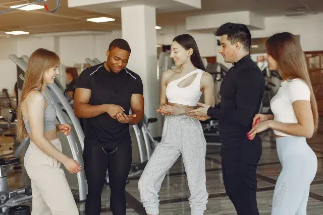 A group of people in a gym engaged in conversation, highlighting successful strategies for gym ownership.