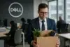 A man in a suit holds a cardboard box containing a plant and office supplies, standing in a modern Dell office environment.